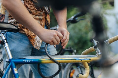 Two hands grasp a black tube attached to a bicycle.